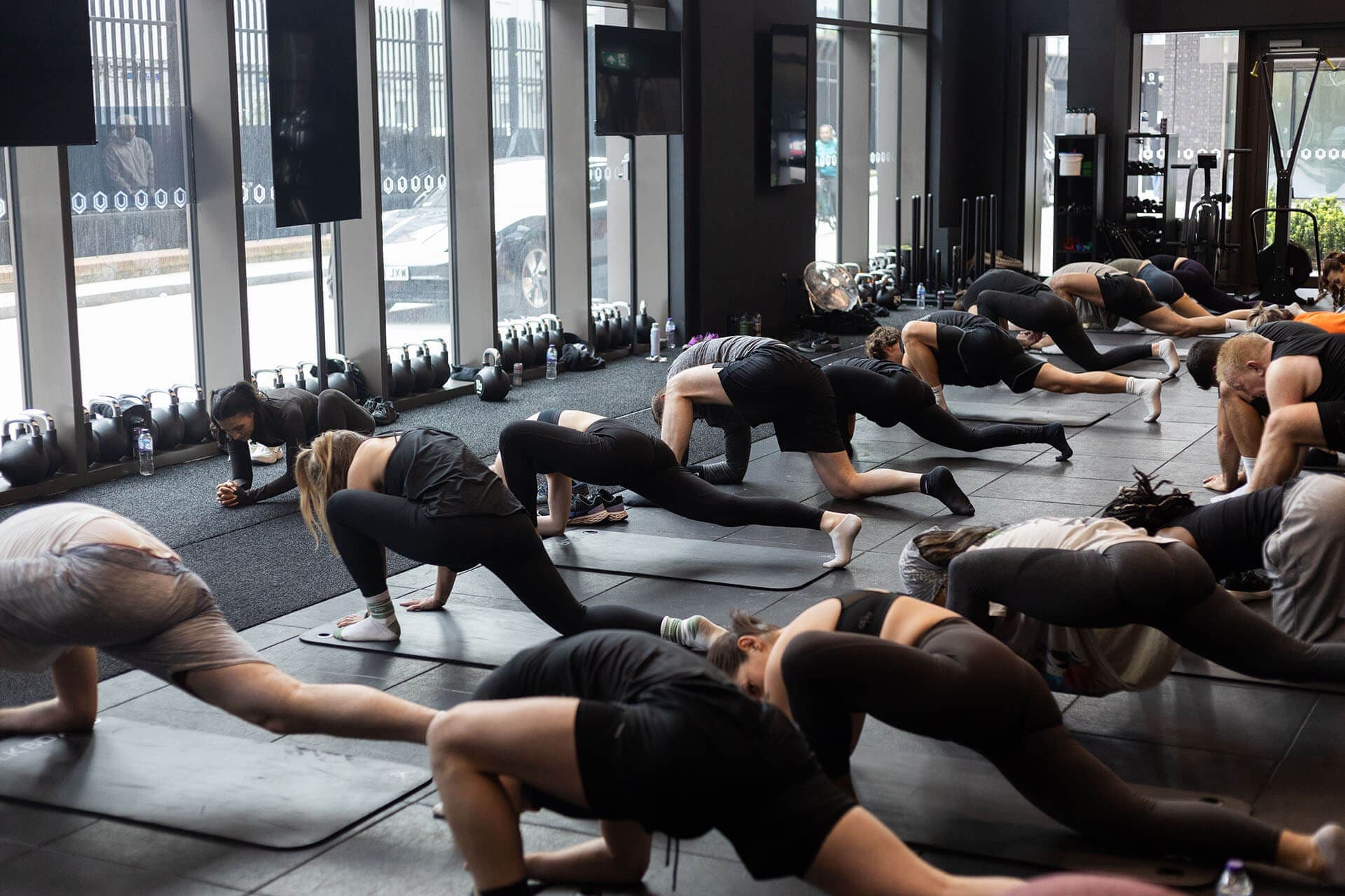 A full class working through floor mobility on mats in a London studio